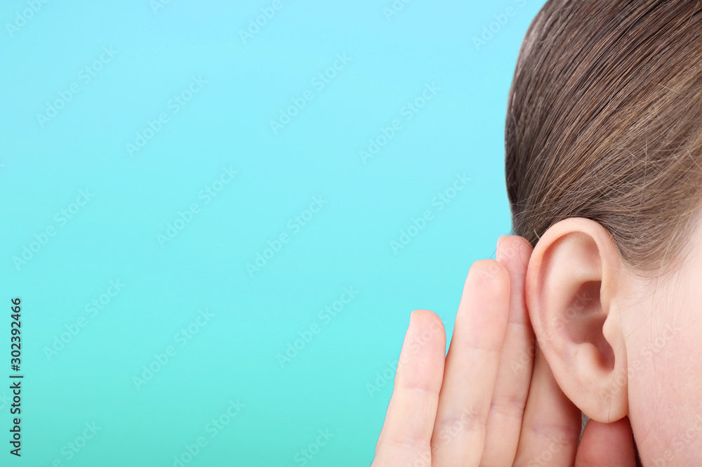 The girl listens attentively with her palm to her ear close-up, news concept - obrazy, fototapety, plakaty 