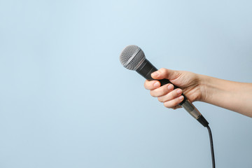 Female hand with microphone on color background