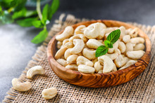 Cashew Nuts In A Wooden Bowl On Dark Stone Board With Blurred Background.