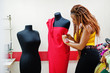 Young african dressmaker woman designed new red dress on mannequin at tailor office. Black seamstress women.