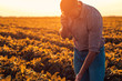 © Zoran Zeremski - Young farmer in filed examining soybean corp and talking at phone.