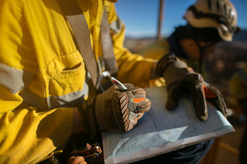 Construction workers wearing a industry safety glove signing of high risk working at height permit on the opening field prior starting early day shift