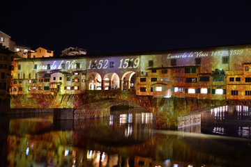 Wall Mural - Italy, Florence, December 2018: The famous Ponte Vecchio of Florence illuminated in occasion of F-Light - Festival of Lights with the masterpieces of Leonardo da Vinci during the Christmas season.