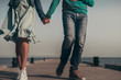 © Aleksandra - lovers in blue clothes, a girl in a dress with a floral print, walk by the hand on a wooden pier against the sea