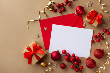 Empty paper blank for Christmas or New year greeting card. Gift boxes, holiday decorations on golden background top view. Flat lay.