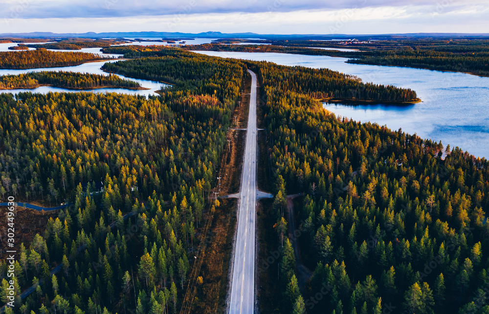 Aerial view of road through autumn forest with blue lakes in Finland. - obrazy, fototapety, plakaty 