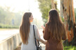 © Antonioguillem - Back view of two women walking and talking in a park