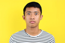 Very Serious Young Asian Man Looking At Camera Isolated On Yellow