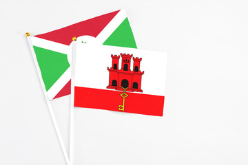 Gibraltar and Burundi stick flags on white background. High quality fabric, miniature national flag. Peaceful global concept.White floor for copy space.