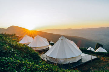 camping and white tent on the green hill with sunset sky background, chiangrai thailand