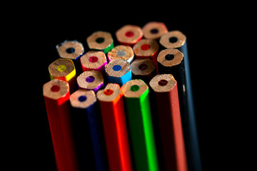 The bottom of the colored wooden pencil on black background. Wooden colored bottoms arranged in clusters