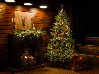 christmas and new year interior - blur background: fireplace, lamps, green christmas tree, brown lea