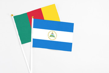 Nicaragua and Cameroon stick flags on white background. High quality fabric, miniature national flag. Peaceful global concept.White floor for copy space.