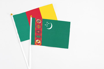 Turkmenistan and Cameroon stick flags on white background. High quality fabric, miniature national flag. Peaceful global concept.White floor for copy space.