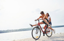 Two Female Friends On The Bike Have Fun At Beach Near The Lake
