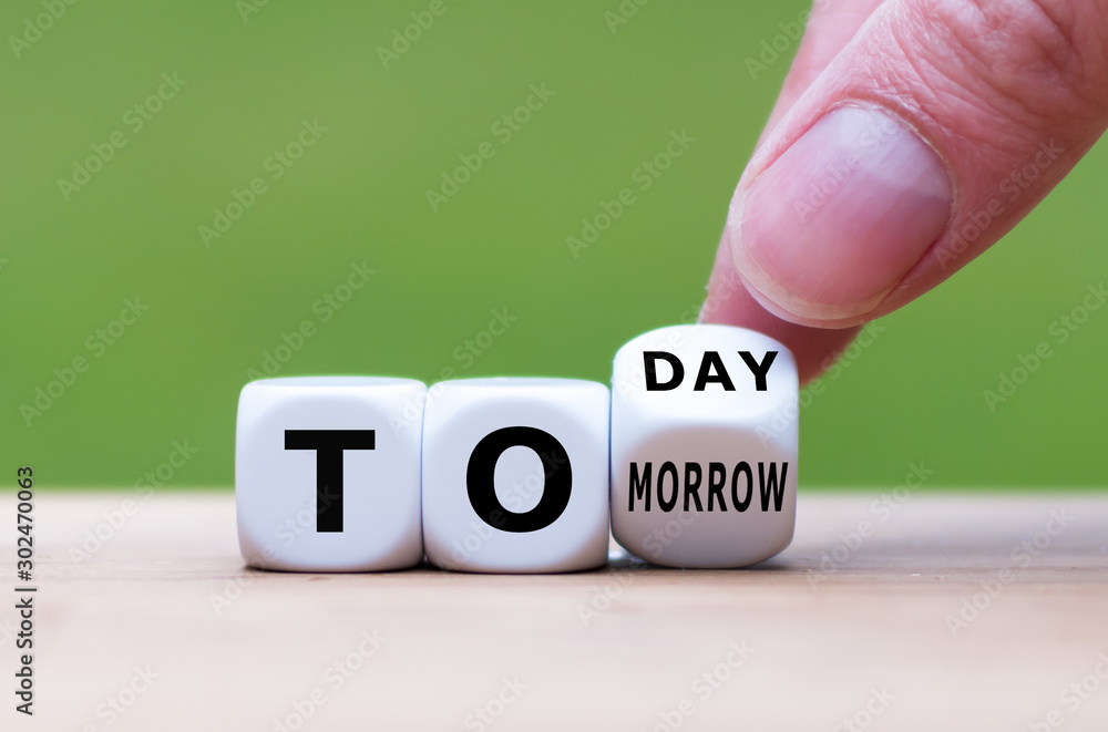 Hand turns a dice and changes the word "tomorrow" to "today", or vice versa. - obrazy, fototapety, plakaty 