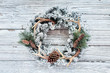 Flocked stylish country or hunters Christmas wreath over white wooden table background.  Wreath is made with pine cones, fir branches, and deer antlers and flocked with fake snow. Handmade decor. 