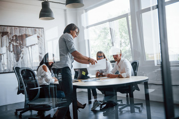 Some documents on the table and in hands. Young business people in formal clothes working in the office