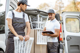 Fototapeta  - Delivery company employees unloading cargo van vehicle, delivering some goods and furniture to a clients home. Relocation and professional delivery concept