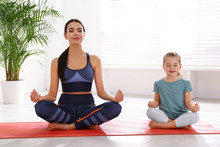 Woman And Daughter Meditating Together At Home. Fitness Lifestyle