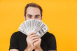 © Drobot Dean - Image of young man wearing basic black t-shirt holding money cash