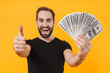 Image of unshaved man wearing t-shirt smiling and holding money cash