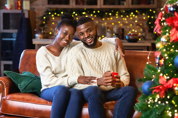 Wall Mural - Afro couple enjoying Christmas eve, embracing and smiling at camera