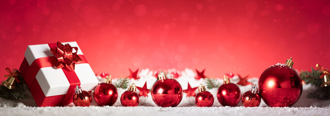 panoramic image of gift box and red christmas balls on snow