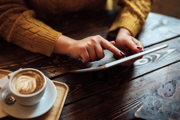 Wall Mural - Woman uses tablet at desk in cafe, top view