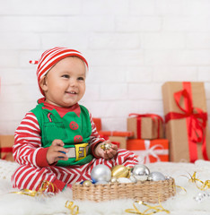 Wall Mural - Cheerful baby elf playing with Christmas decorations at home