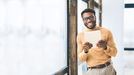 Smiling afro businessman using tablet, looking at camera