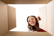 surprise, delivery and holidays concept - happy young woman looking into open gift box