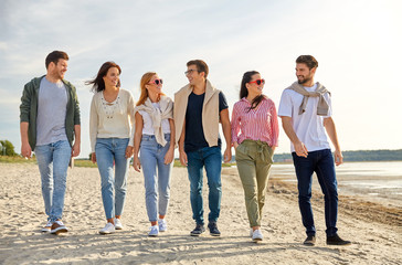 Canvas Print - friendship, leisure and people concept - group of happy friends walking along beach in summer