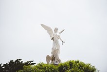 White Female Statue With Wings And A Cloudy Sky