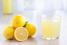 A Glass Of Lemon Juice And Lemons Around On A Table.