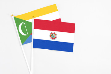 Paraguay and Comoros stick flags on white background. High quality fabric, miniature national flag. Peaceful global concept.White floor for copy space.