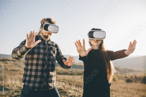 Innovation VR technology concept, two people in virtual reality box glasses  gadget technology on road in forest on hills nature background, two people  use headset digital for entertainment experience - Buy this