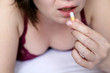© Oleg - Woman taking pill in the bed, girl in lingerie with capsule in hand. Concept of illness, taking medication, sleeping pill, contraception, vitamins or sedative