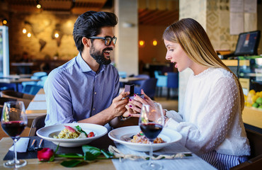 Young man surprised his girlfriend with engagement ring in the restaurant. Lifestyle, love, relationships, food concept