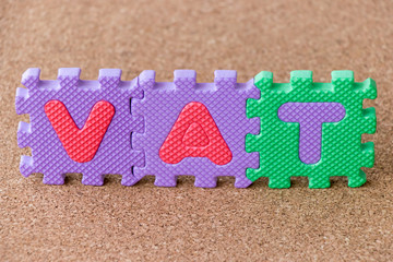 Poster - Colorful toy foam alphabet in word VAT on cork board background