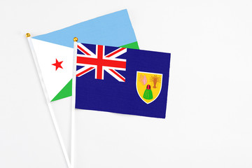 Turks And Caicos Islands and Djibouti stick flags on white background. High quality fabric, miniature national flag. Peaceful global concept.White floor for copy space.