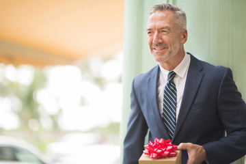 Mature handsome businessman holding a present.