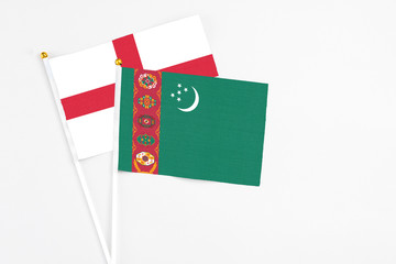 Turkmenistan and England stick flags on white background. High quality fabric, miniature national flag. Peaceful global concept.White floor for copy space.