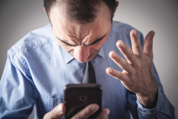 Wall Mural - Angry caucasian businessman with smartphone.