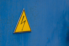 Warning Sign Of High Electrical Voltage. Yellow Sign On Blue Background