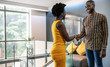 © JonoErasmus - Two successful black business people shaking hands in modern office space. Wearing african inspired clothing