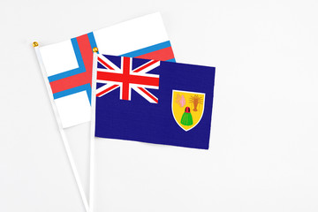 Turks And Caicos Islands and Faroe Islands stick flags on white background. High quality fabric, miniature national flag. Peaceful global concept.White floor for copy space.