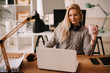 © JustLife - Young businesswoman in office. Beautiful woman with headphones drinking coffee.