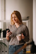 © JustLife - Young businesswoman in office. Beautiful woman drinking coffee and typing message.