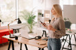 © JustLife - Young businesswoman in office. Beautiful woman drinking coffee and typing message.